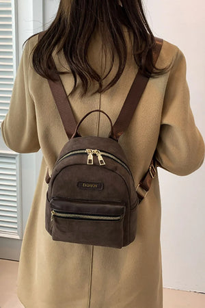 Coffee brown suede mini backpack with golden zips and front pocket.