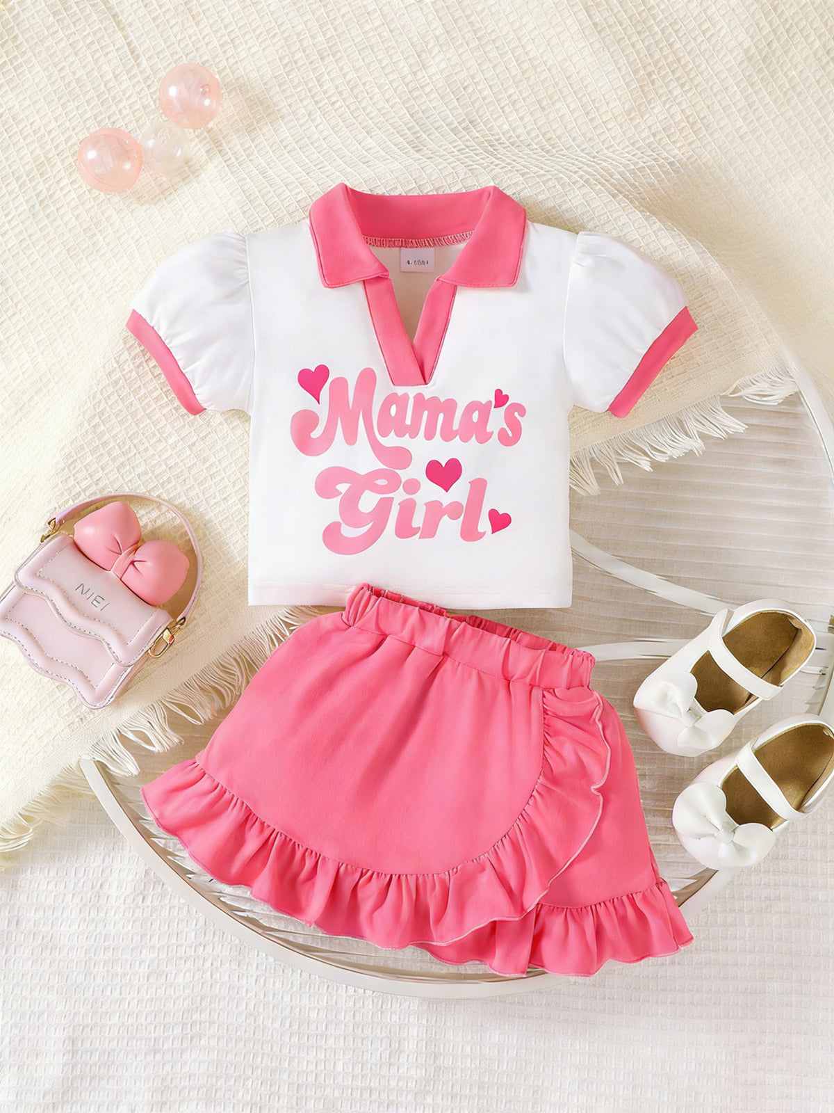 White short sleeve top with pink trim and "Mama's Girl" graphic, paired with a bright pink ruffle skirt.