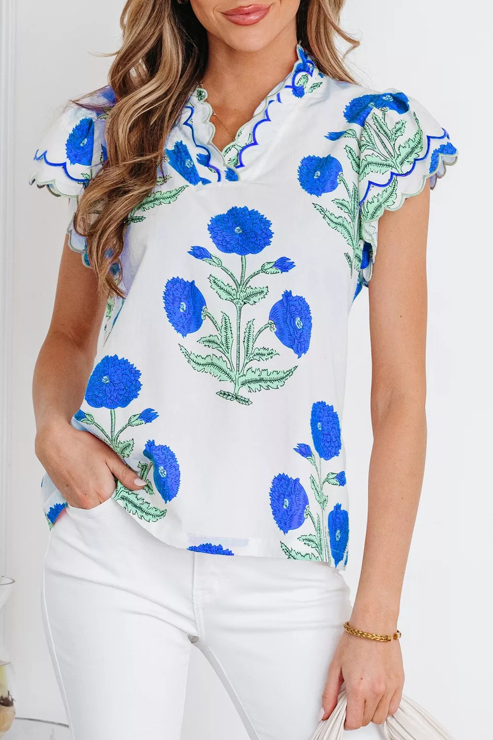 White cotton blouse with vibrant blue floral print and scalloped trim sleeves and neckline.