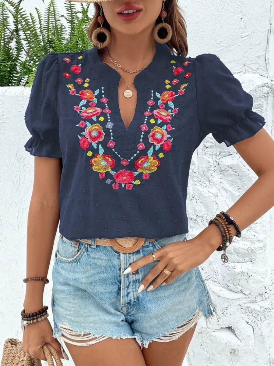 Navy blue blouse with floral embroidery, puff sleeves, and textured fabric.
