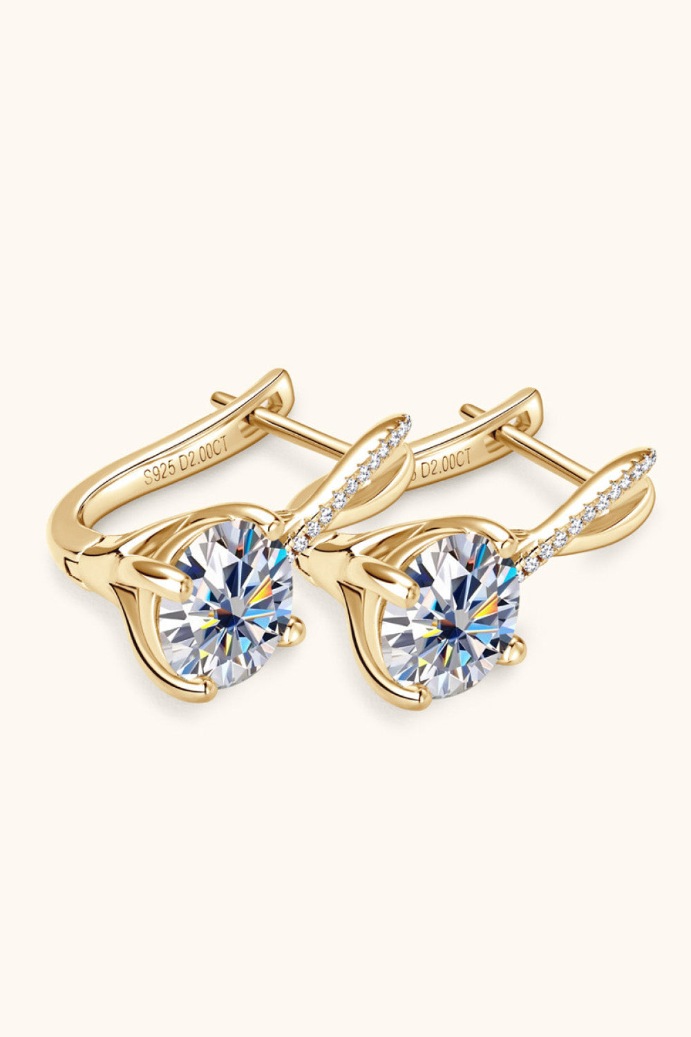 Gold crossover moissanite huggie earrings with diamond accents and large center stones.