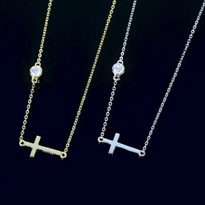 Asymmetrical cross pendant necklaces in gold and silver with a single crystal accent.