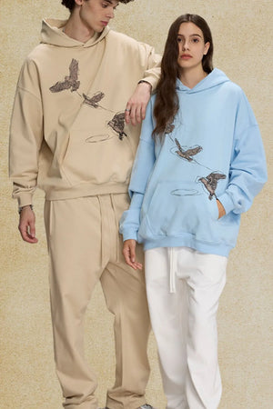 Embroidered flight hoodie in light blue with bird graphic, relaxed fit, and front pocket.