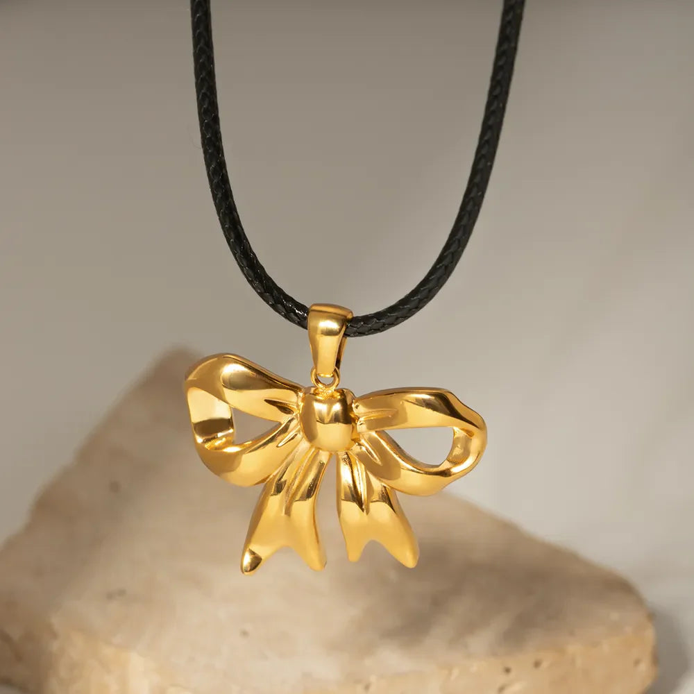 Gold sculptural bow pendant necklace on black wax rope cord