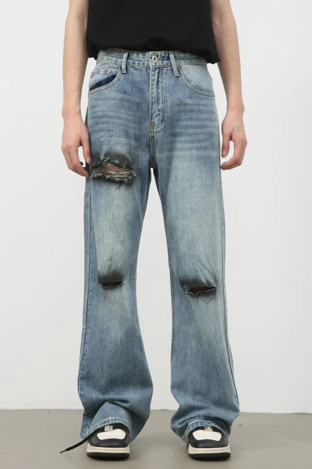 Distressed flare leg jeans in medium wash denim with ripped details.