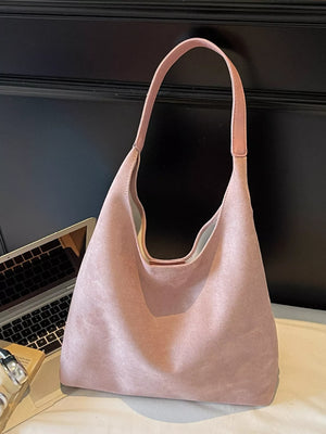 Dusty pink suede shoulder bag with a single strap.