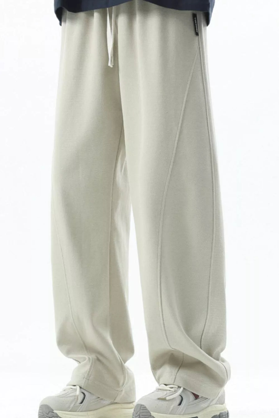 Men's beige loose fit sweatpants with drawstring and curved seam detail.
