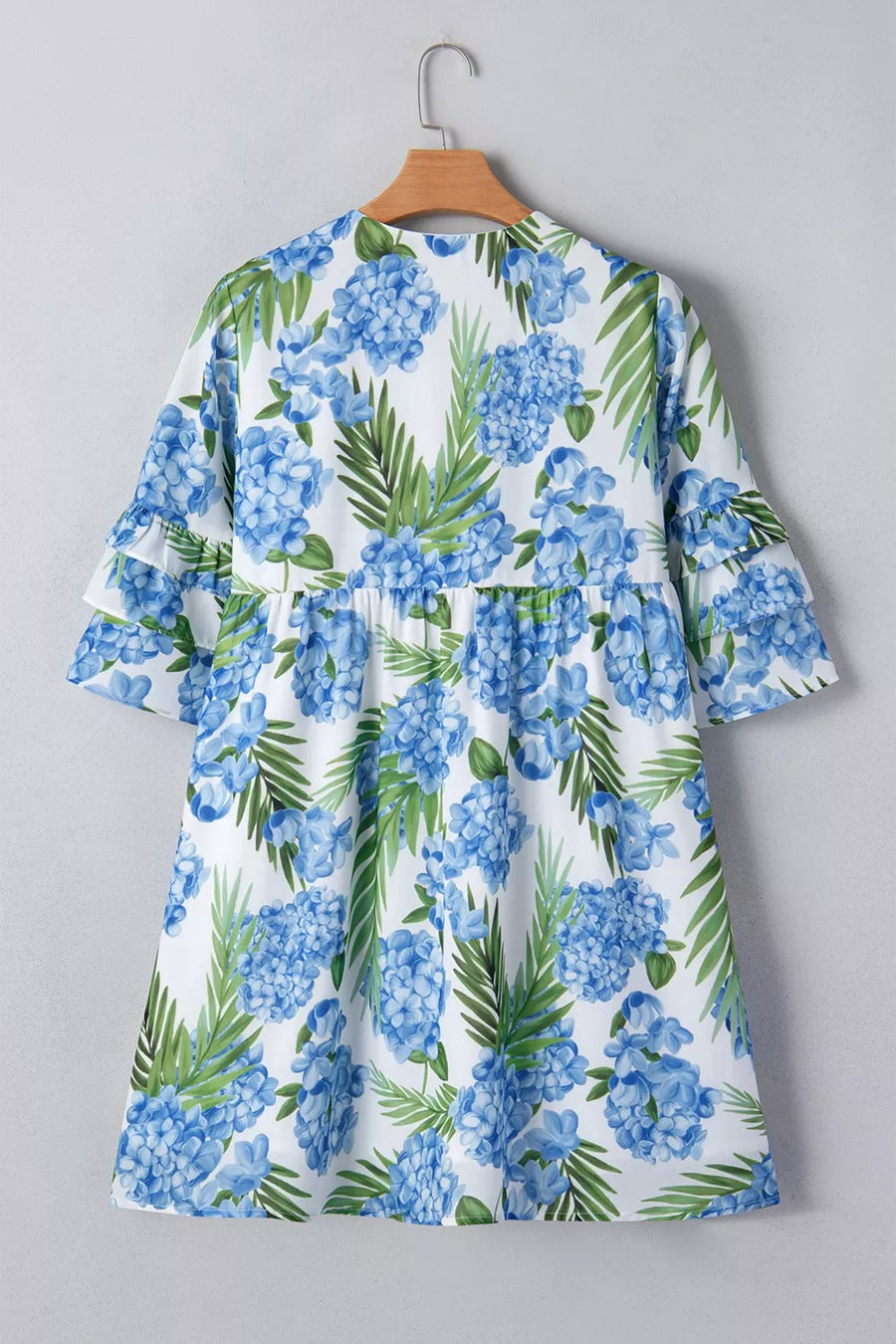 Ruffled mini dress with hydrangea and palm print, featuring a smocked waist and flutter sleeves.