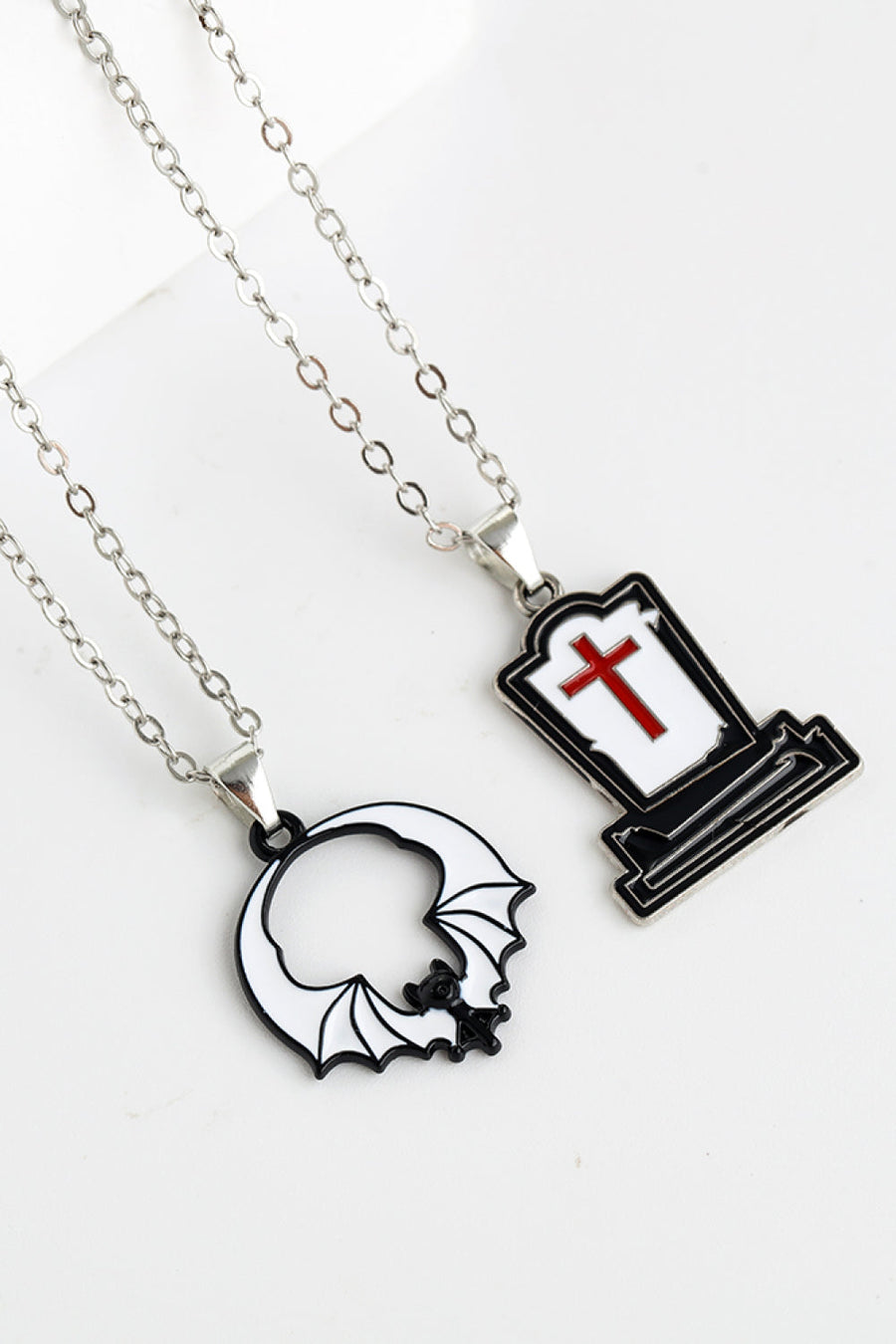 Spooky Season enamel pendant necklaces: tombstone with red cross and bat outline.