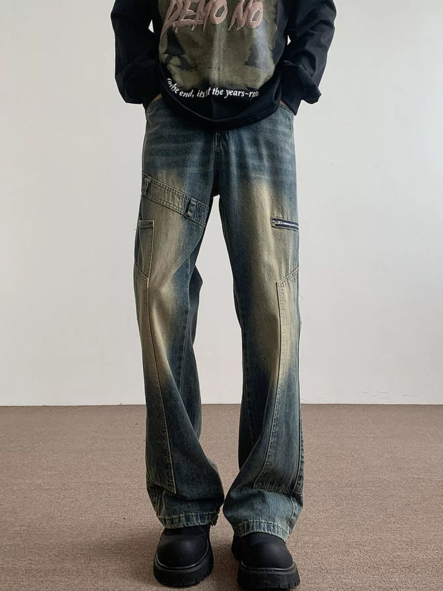 Men's blue vintage wash flare jeans with distressed details and zip pockets.