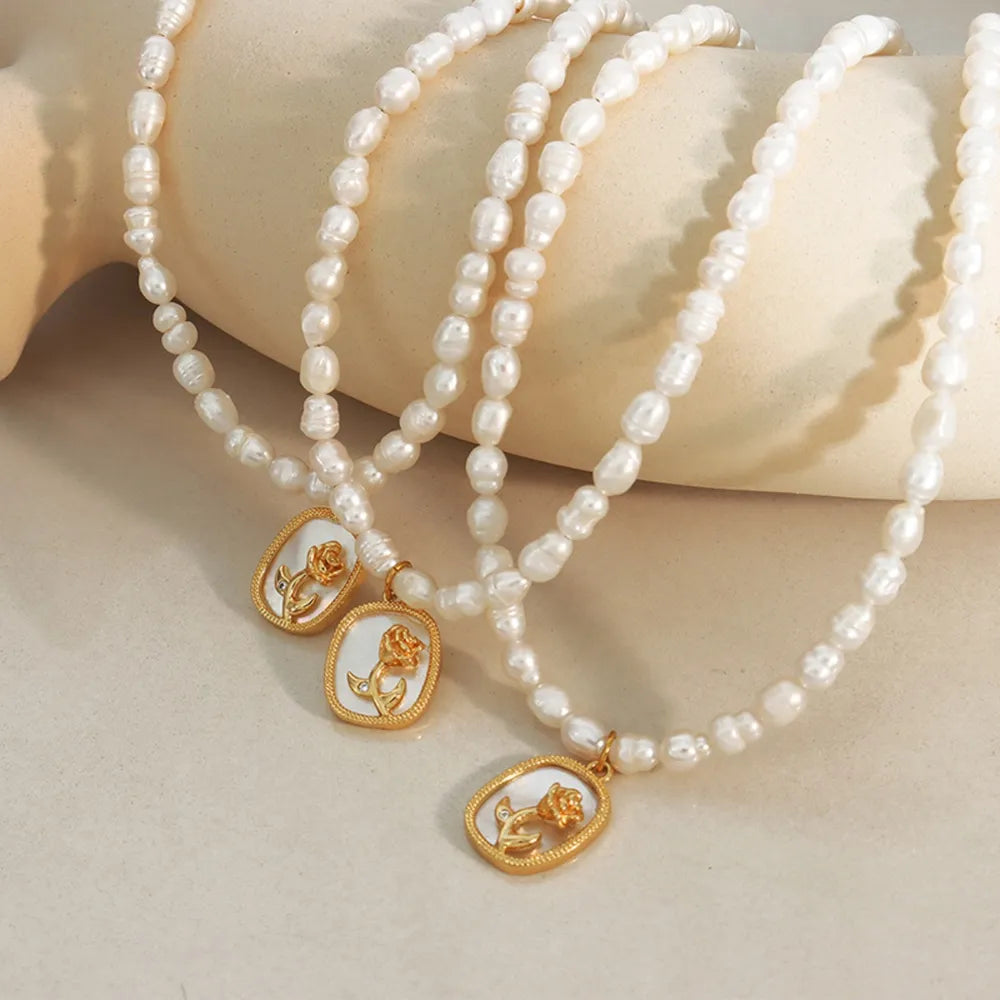 Gold baroque pearl necklace with floral medallion charms and delicate rose detail.