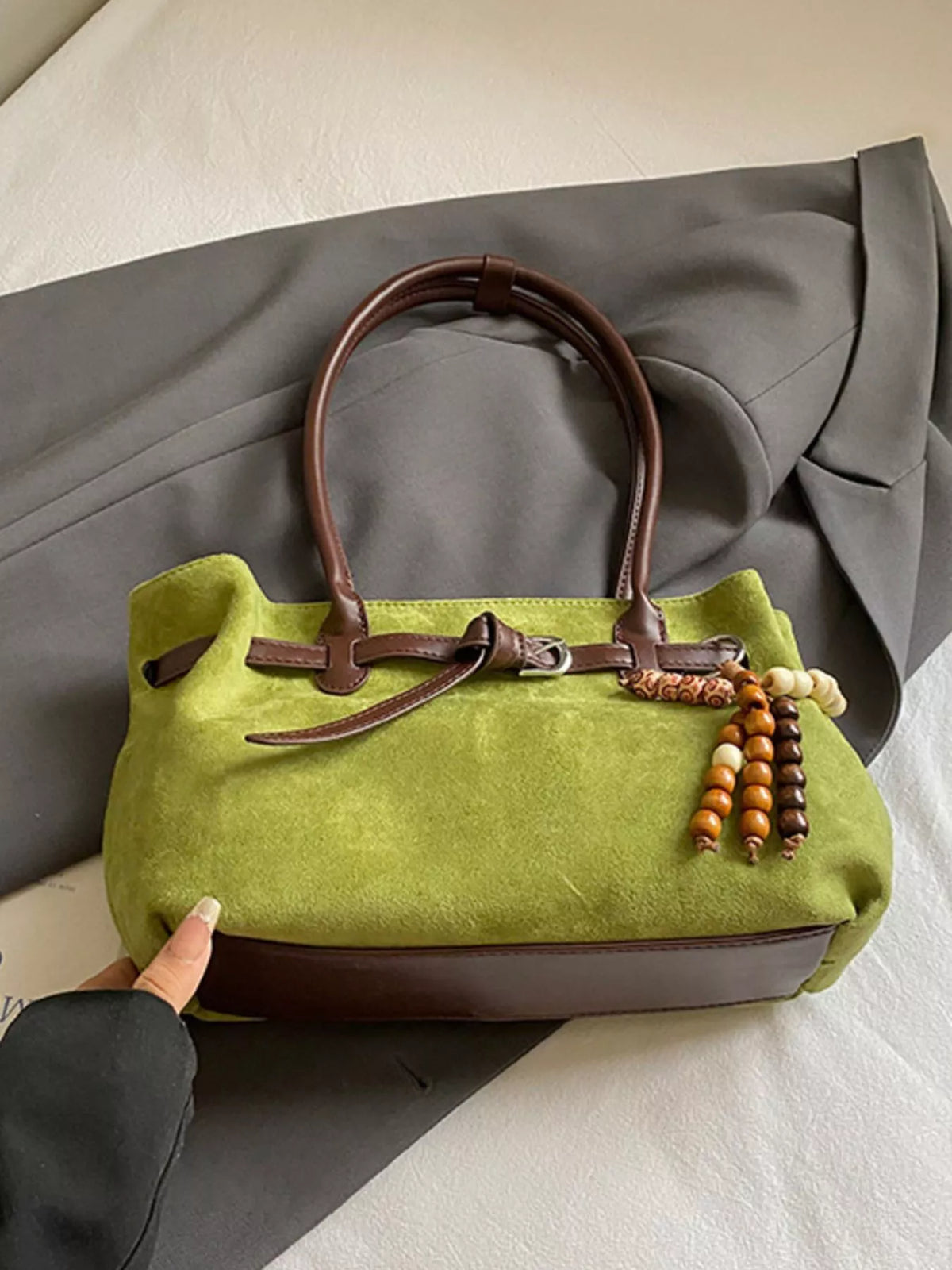 Green suede tote bag with brown leather trim and beaded tassel detail
