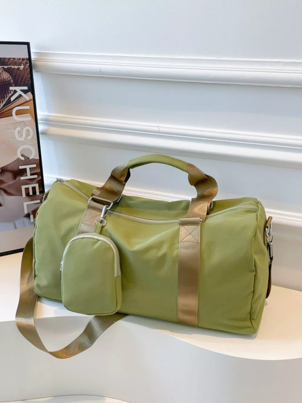 Green duffle bag with detachable pouch and gold straps, perfect for gym or travel.