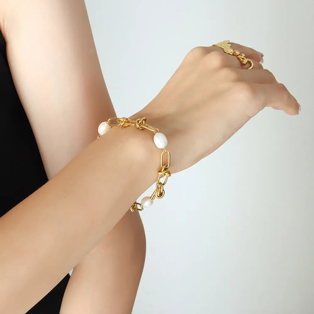 Gold knot and pearl link bracelet with oval pearls on a chain.