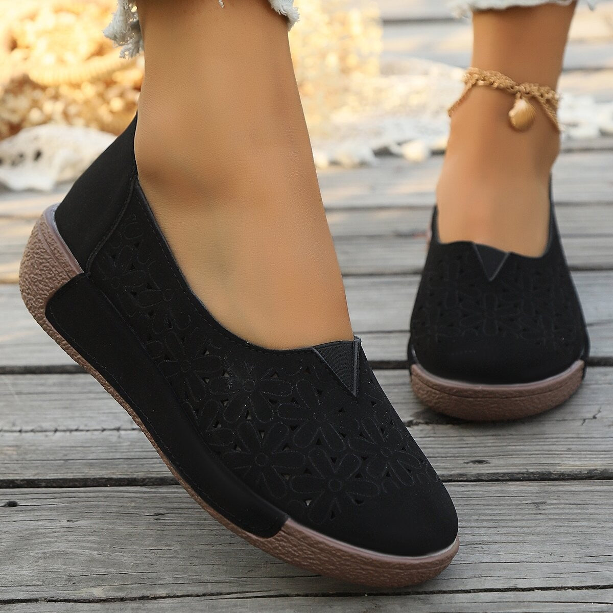 Black floral cutout slip-on loafers with comfortable breathable design.