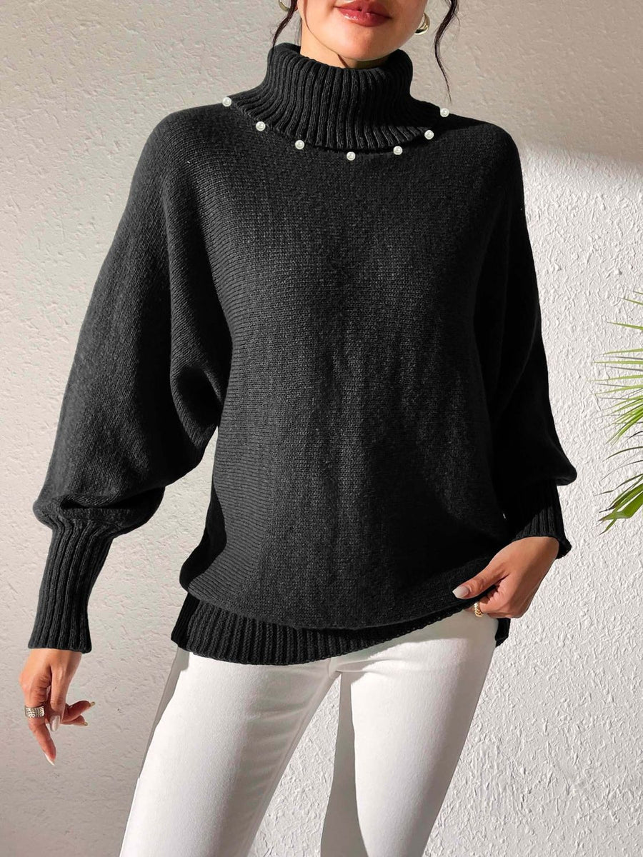Black knit sweater with pearl-embellished turtleneck and dolman sleeves.