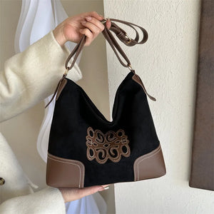Black suede hobo bag with brown appliqué and contrast stitching.