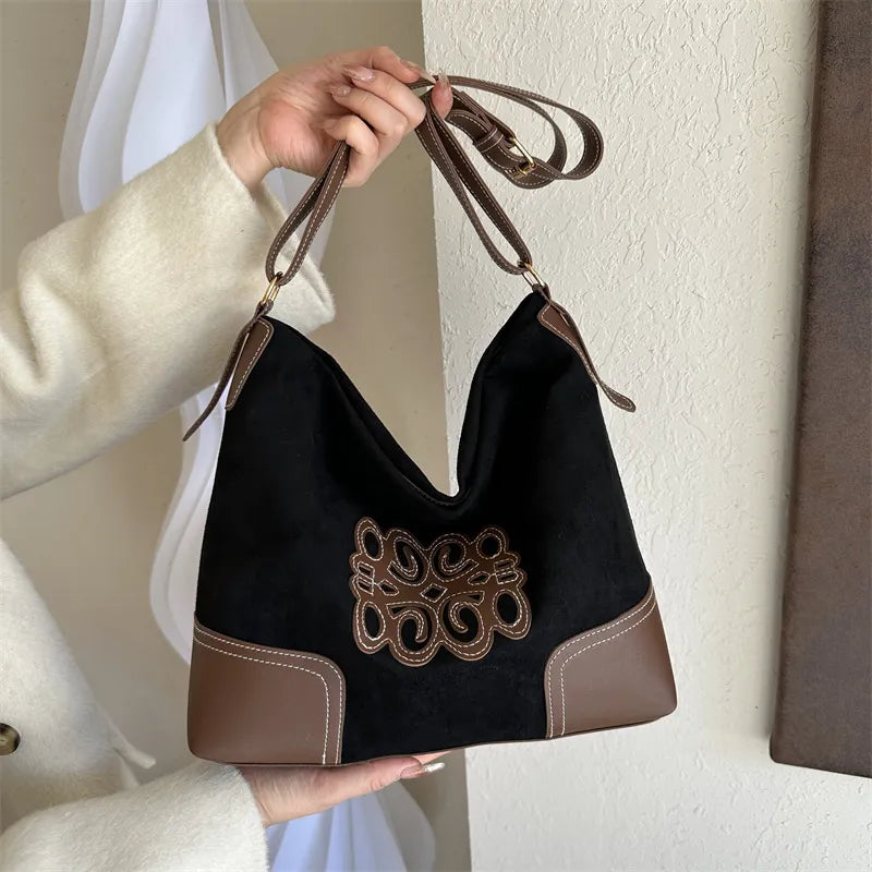 Black suede hobo bag with brown appliqué and contrast stitching.