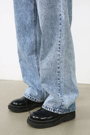 Acid wash wide-leg jeans in medium blue denim, styled with black platform shoes.