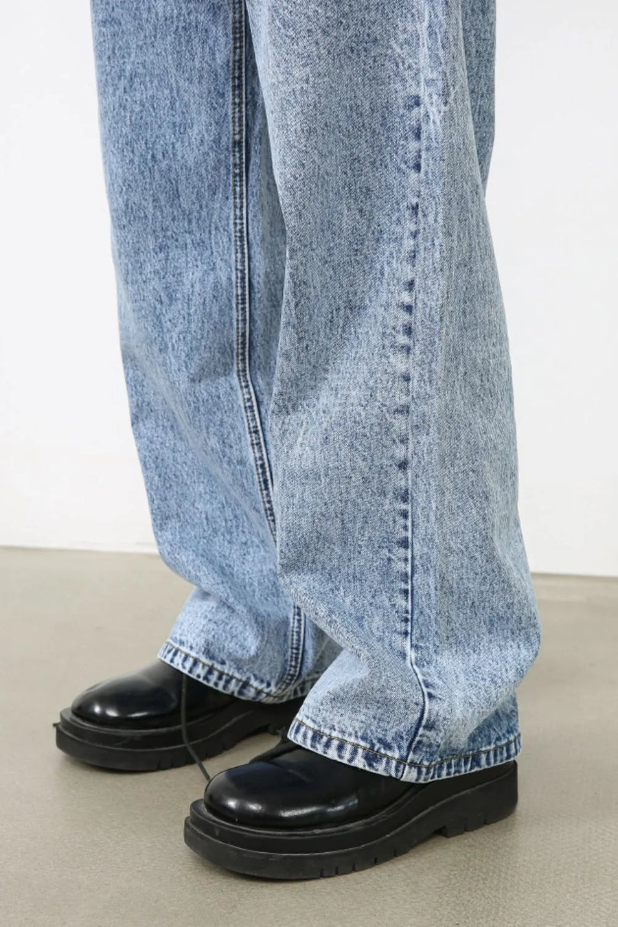 Acid wash wide-leg jeans in medium blue denim, styled with black platform shoes.