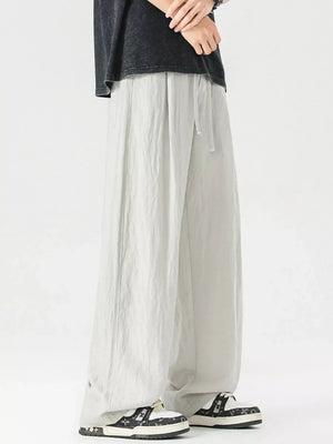 Lightweight wide-leg trousers in light gray with drawstring waist and relaxed fit.