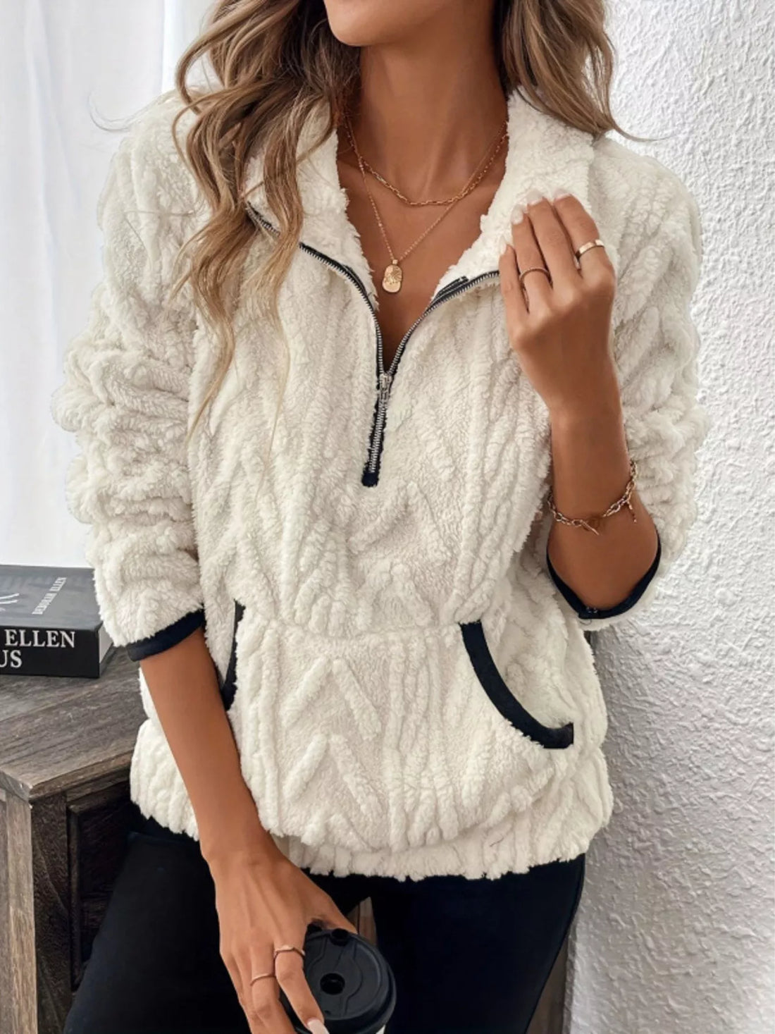 White sherpa half zip sweatshirt with chevron texture and black trim pockets.