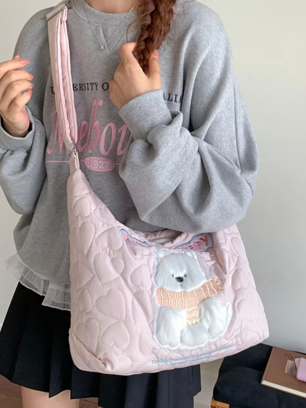 Blush pink quilted crossbody bag with heart pattern and a white bear applique wearing a scarf.