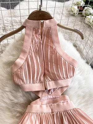Pink pleated maxi dress with cutout detail and halter neckline.