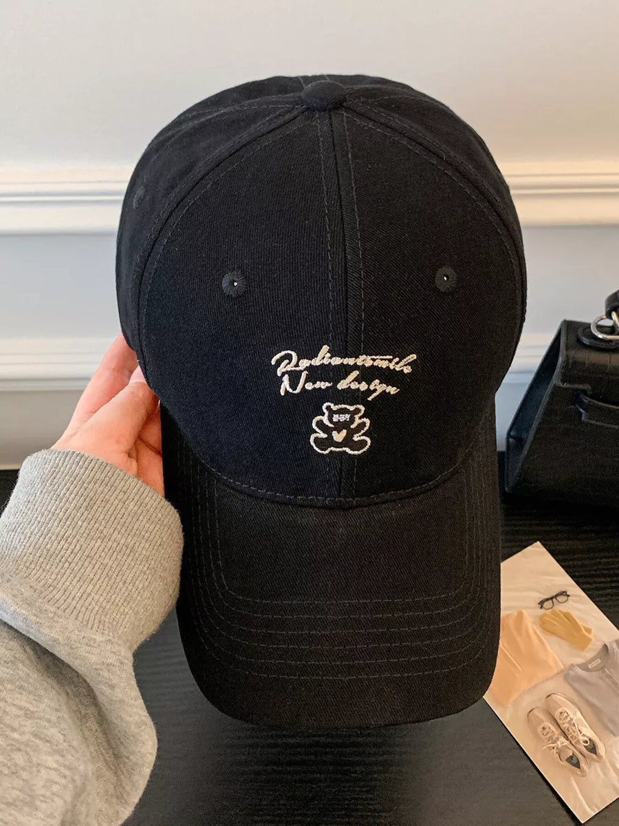 Black baseball cap with embroidered teddy bear and text detail