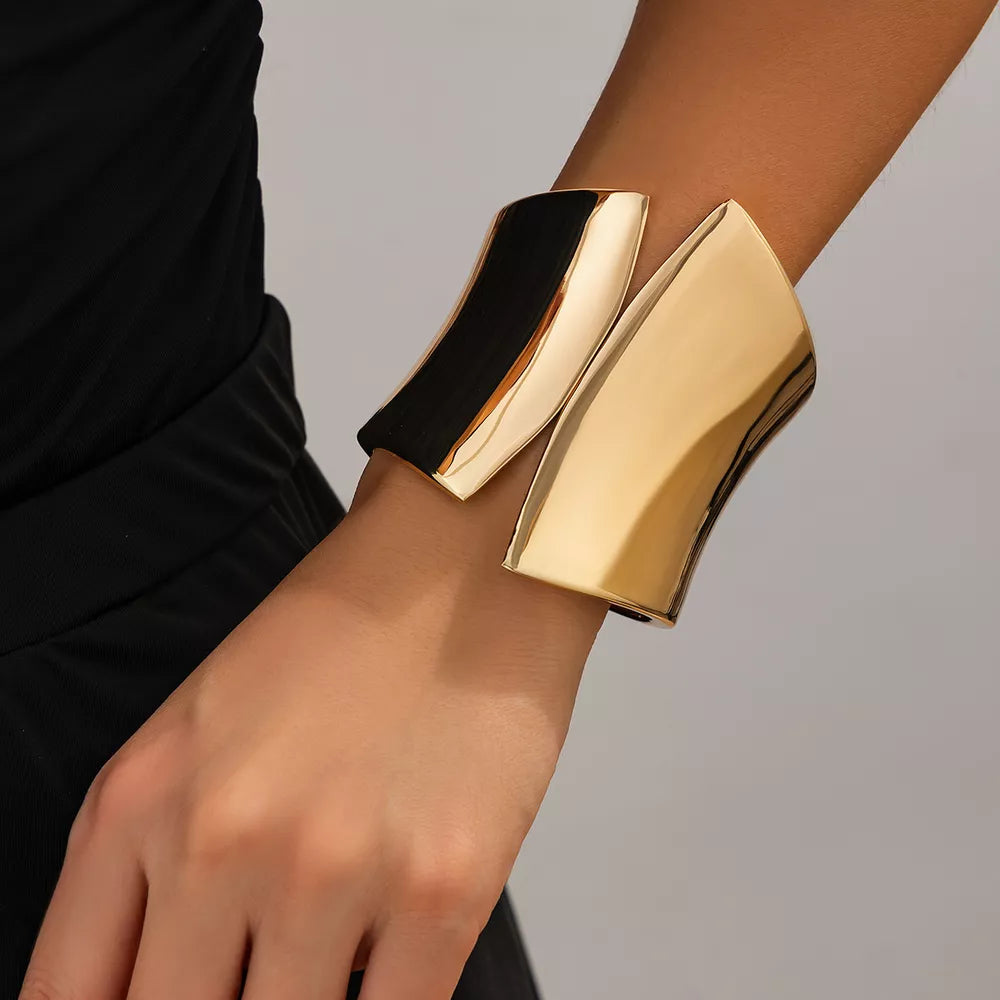Sculptural gold-toned cuff bracelet with a polished finish.