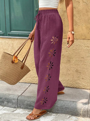 Plum linen pants with drawstring waist and floral cutouts down the side.