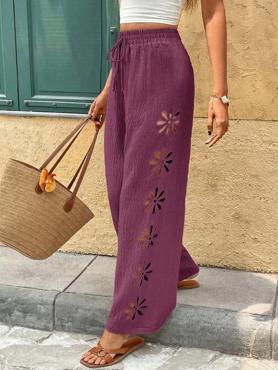 Plum linen pants with drawstring waist and floral cutouts down the side.