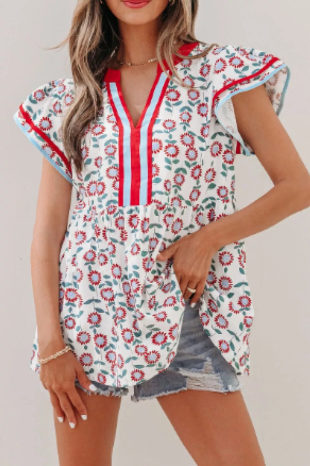 Vibrant floral cotton blouse with ruffle sleeves and a V-neck featuring red and blue stripes.