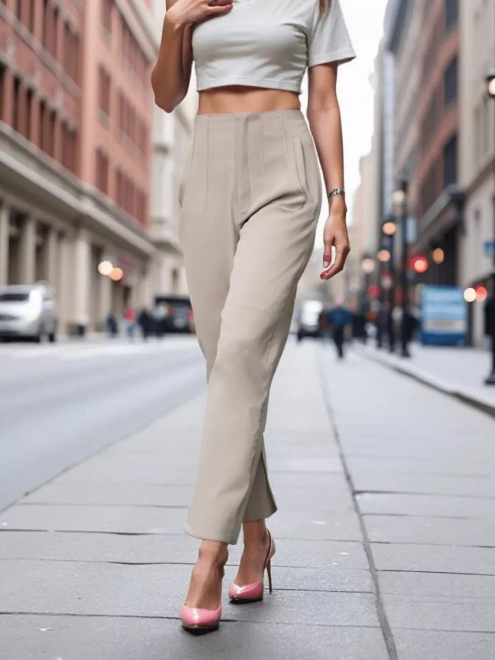 Beige high-waisted straight-leg pants with subtle pleats, styled with pink heels.