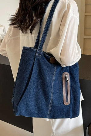 Denim shopper tote bag in dark blue with leather trim and zipper pocket detail.