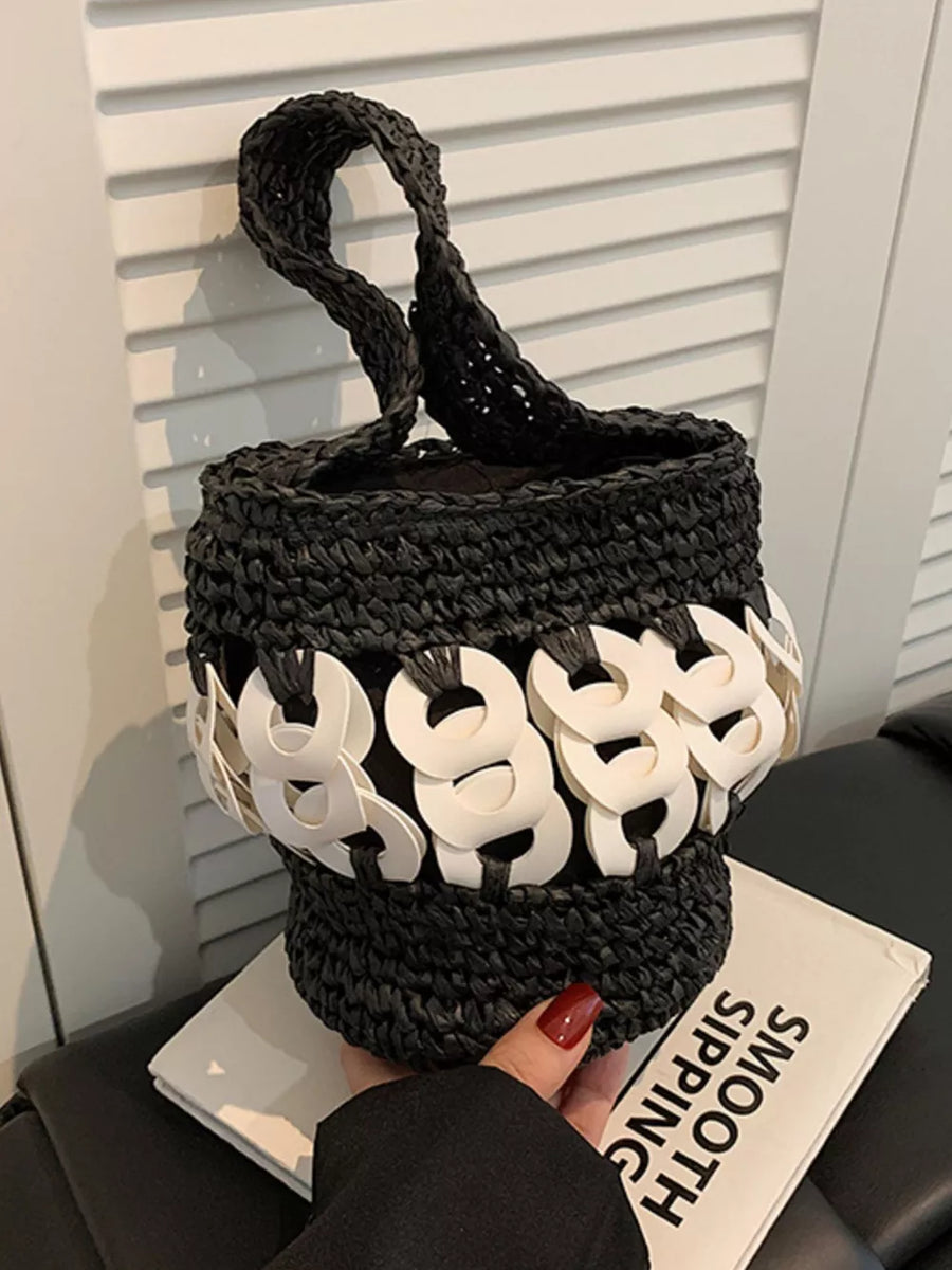 Black woven straw bucket tote with white ring detail and braided handle.