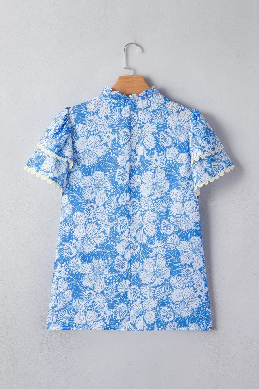 Blue floral print polyester blouse with frill neckline and scalloped sleeves.