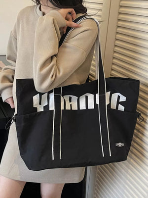 Black drawstring shoulder bag with bold white lettering and side pockets.
