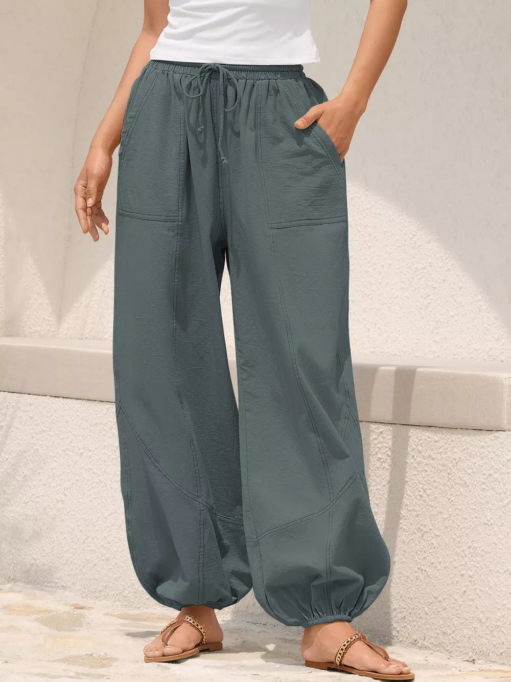 Grey relaxed harem pants with drawstring and contrast stitching, cuffed ankles.