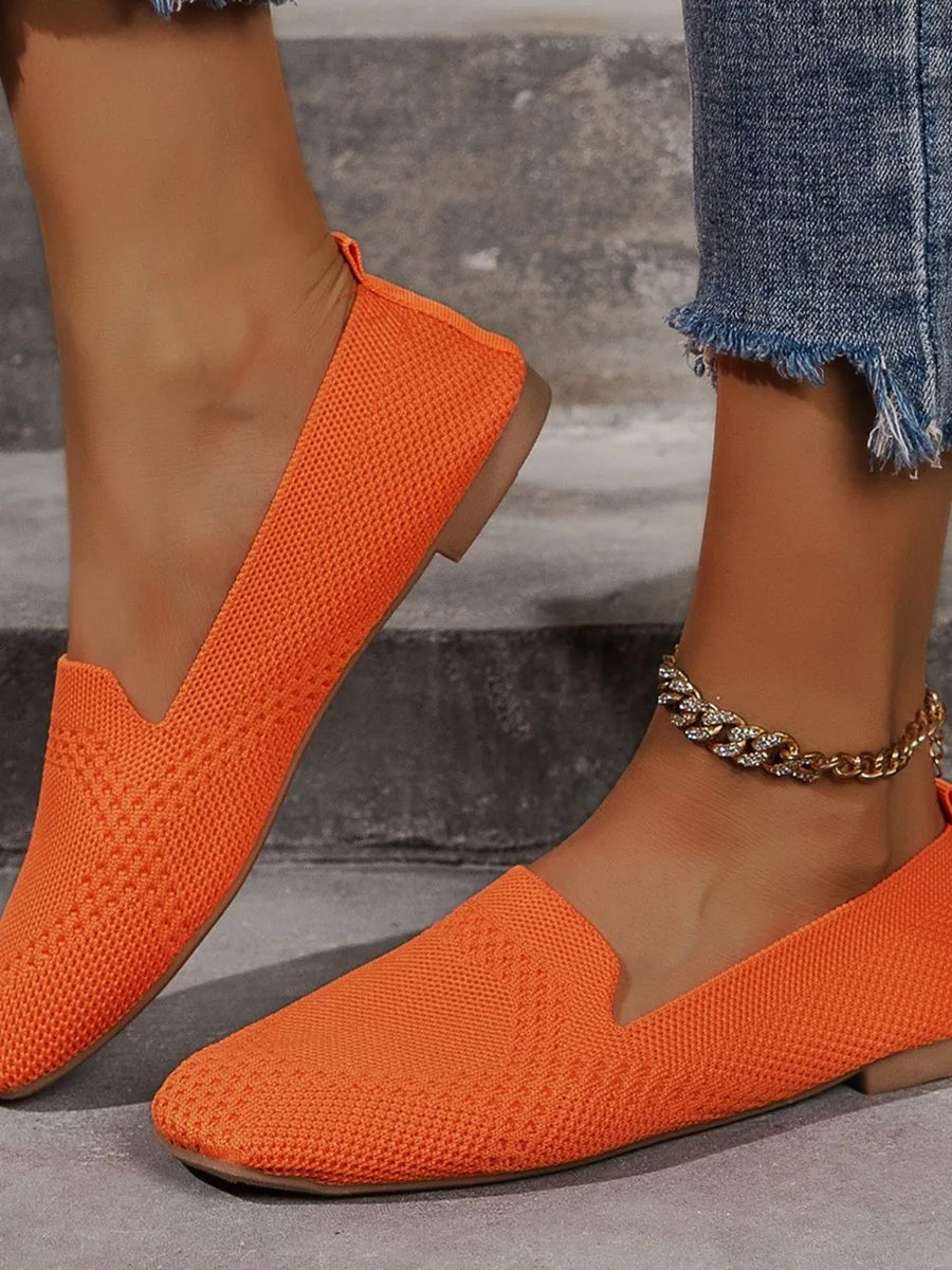 Orange knit ballet flats with a pointed toe and a pull tab.