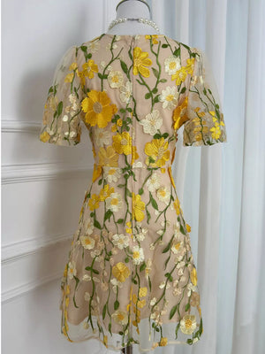 Sheer mesh dress with yellow and white floral embroidery, short puff sleeves, and a round neckline.