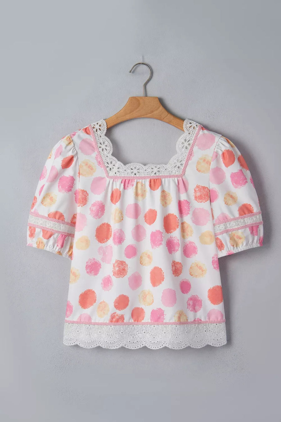 Blouse with polka dot print, square neck, puff sleeves, and lace trim.