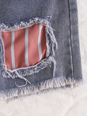 Distressed denim shorts with pink and blue striped lining and frayed hem.