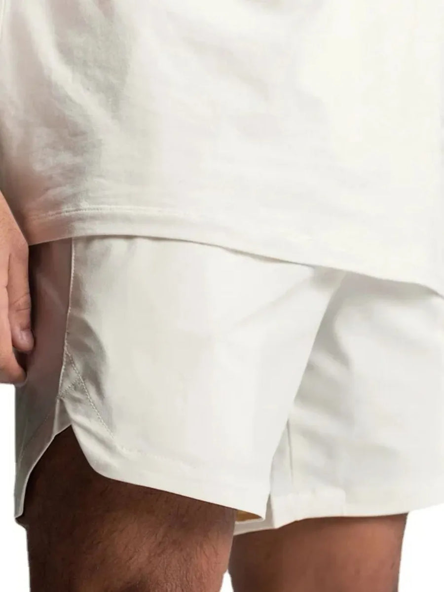 White performance shorts with side vents and a drawstring waist, shown on a model.