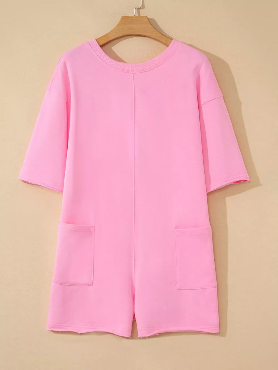 Pink cotton romper with half sleeves, crew neck, and two front pockets.