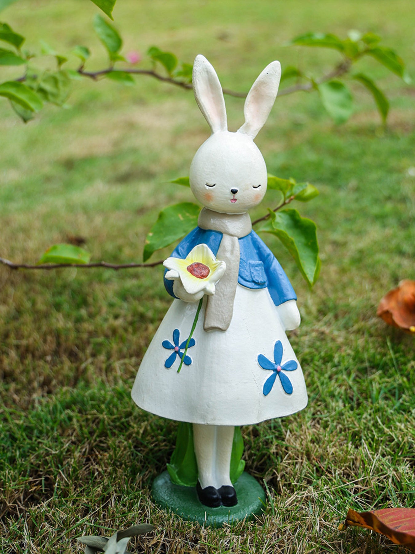 Floral rabbit ornament in blue jacket and white floral dress, holding a flower.