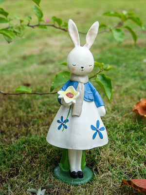 Floral rabbit ornament in blue jacket and white floral dress, holding a flower.