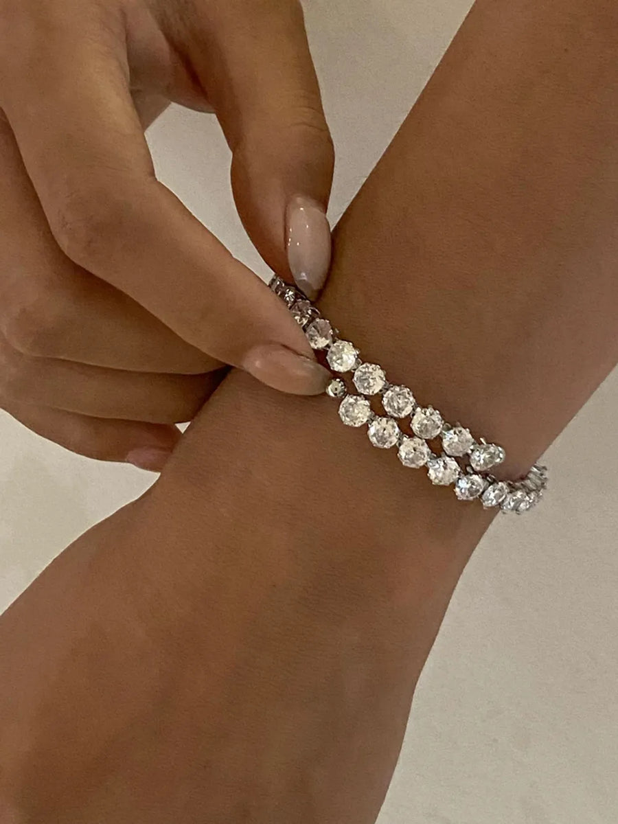 Silver double row pavé bangle bracelet with clear stones on a wrist.
