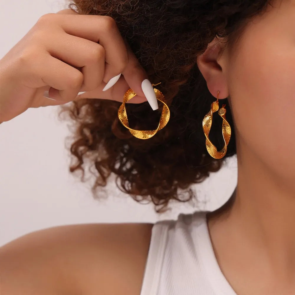 Textured spiral gold hoop earrings with a twisted design.