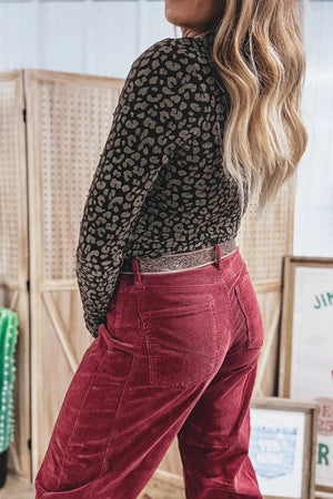 Textured leopard print fitted pullover shirt in black and tan polyester with long sleeves.